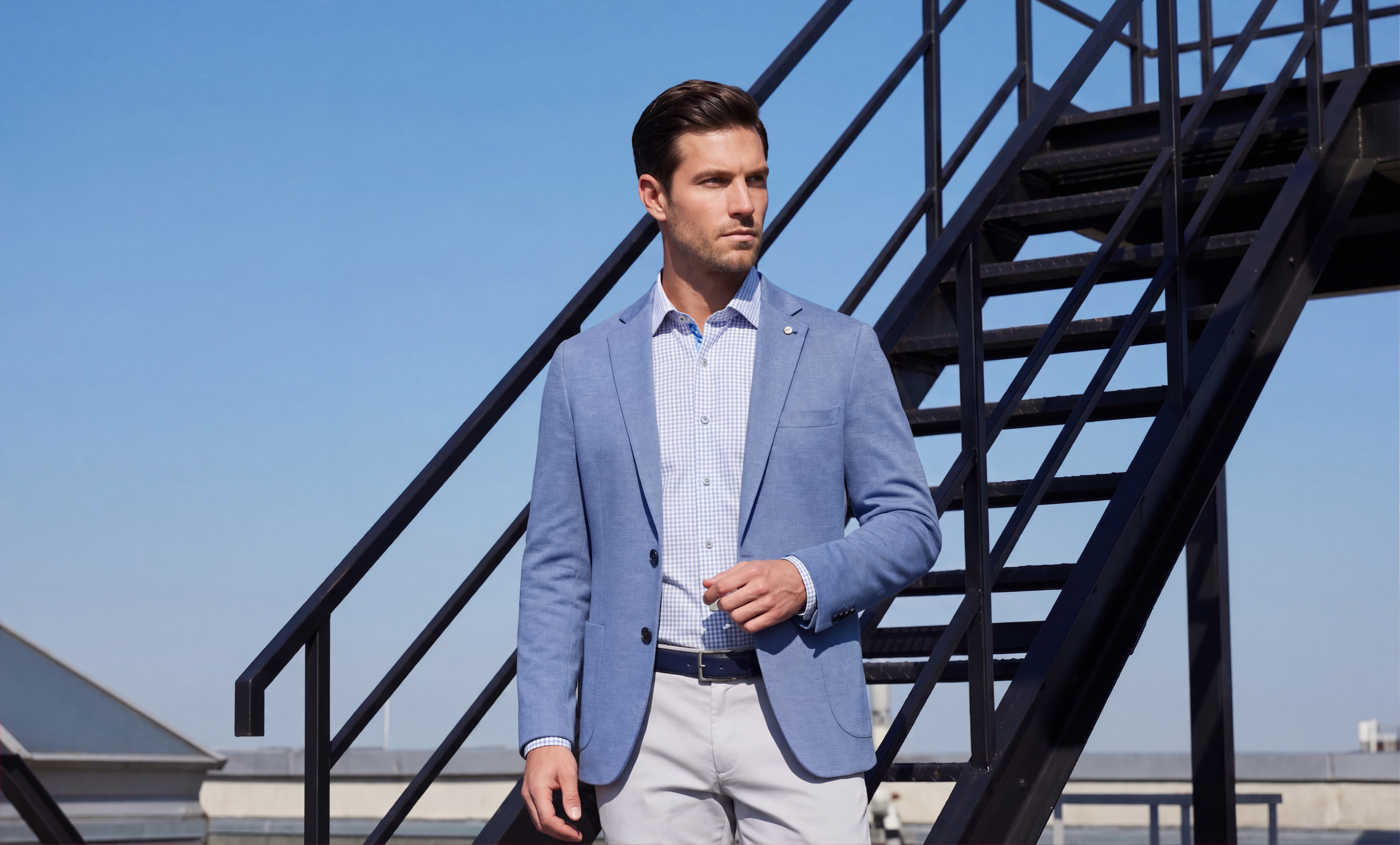 Man wearing a light blue sportcoat on a rooftop stairway